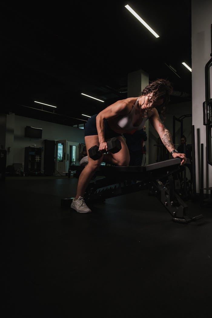Woman working out in a gym, emphasizing strength and fitness with dumbbells.