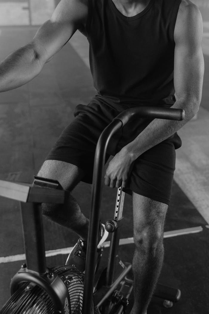 Monochrome image of a man on exercise bike, focused workout session.